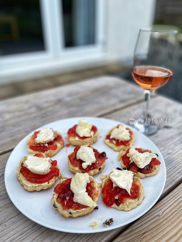 Plate of Cornwall cream scones on a picnic bench alongside a glass of rosé